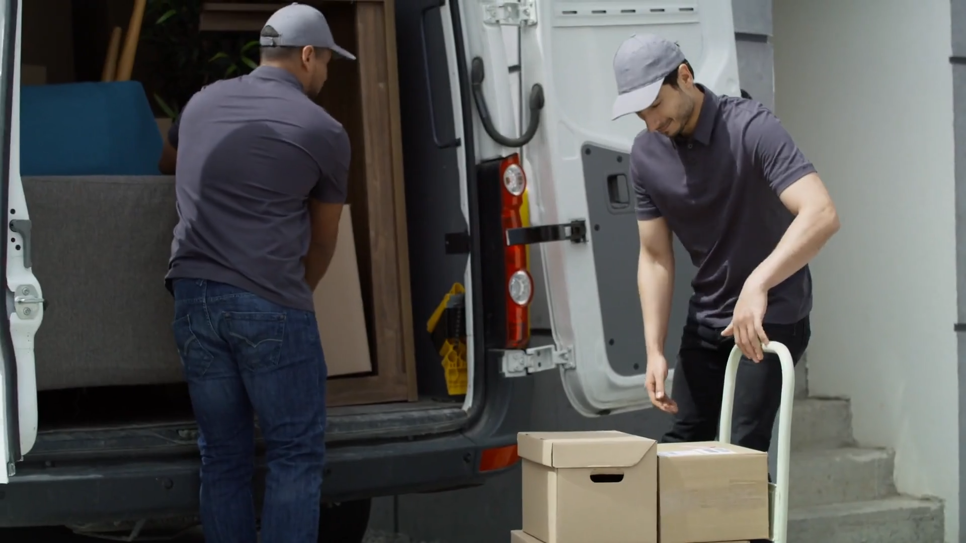 Zdjęcie przedstawia dwóch mężczyzn którzy załadowują samochód dostawczy ładunkami drobnicowymi