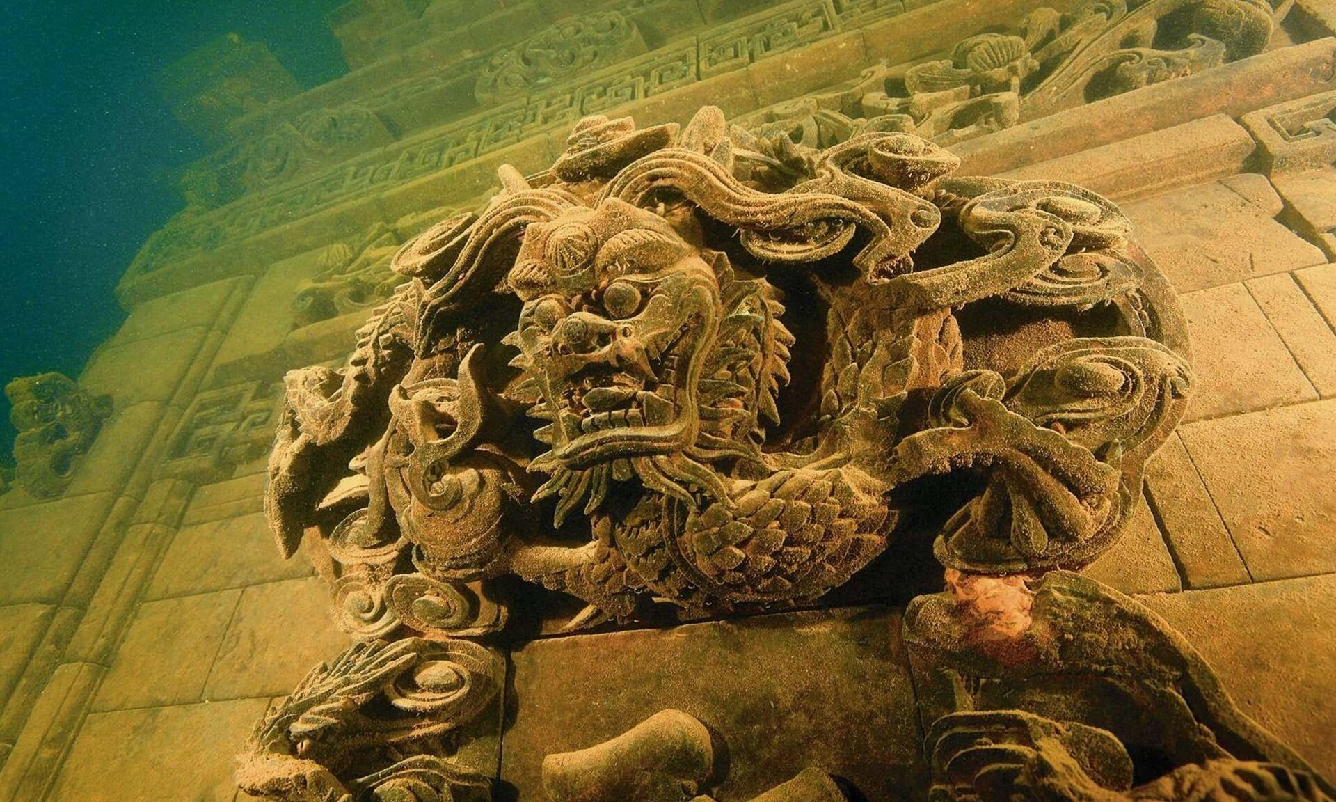 Ilustracja ukazuje ścianę zatopionych ruin budynku, wykonaną z cegły. Na tej ścianie wyróżnia się niezwykły detal w postaci głowy lwa, z wyraźnie zaznaczoną grzywą w formie zwiniętych pasm. Na górnej części ściany także widoczne są dodatkowe detale.