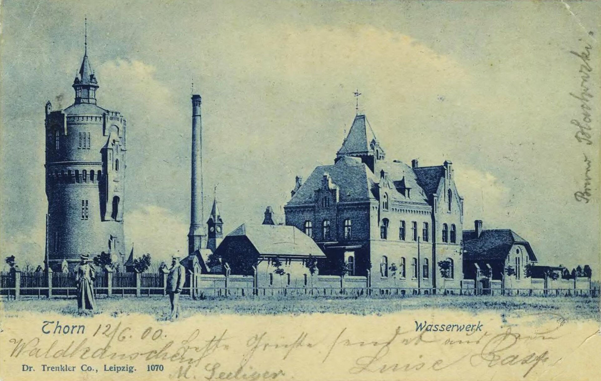 Zdjęcie przedstawia panoramę miasta. Na jej tle  stoi kobieta i mężczyzna na polu. Miasto składa się z wieży, obok niej stoi komin i dom, dalej znajduje się większa zabudowa, a zaraz za nią kolejne niższe domy.