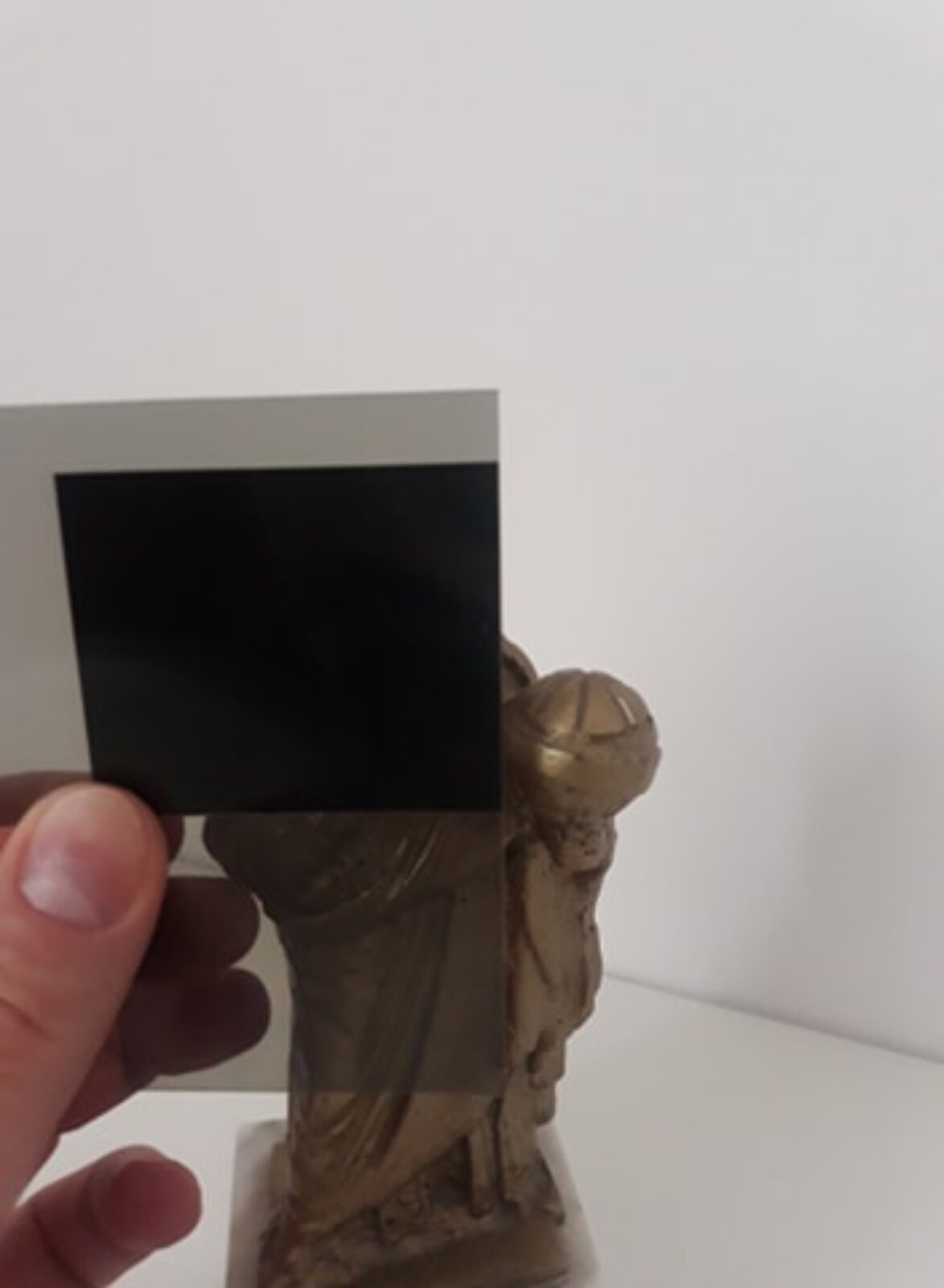 Rys. B. przedstawia wizerunek Mikołaja Kopernika oglądany przez dwa polaryzatory ustawione prostopadle. Widać fragment figury odlanej z brązu na tle szarej ściany. Światło spolaryzowane przez pierwszy polaryzator jest całkowicie wygaszone przy przejściu przez drugi polaryzator. Do obserwatora nie dociera światło z uwagi na to, że zostało całkowicie wygaszone. Polaryzatory ułożone jeden przy drugim dają obraz w postaci czarnego prostokąta.