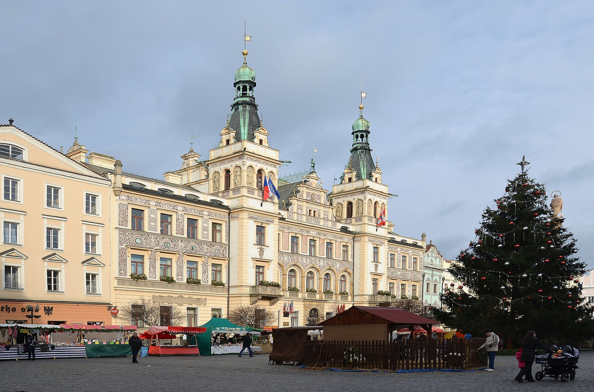 Zdjęcie przedstawiające ratusz miejski w Pardubicach - budynek koloru jasnobeżowego z dwiema zielonymi wieżami.