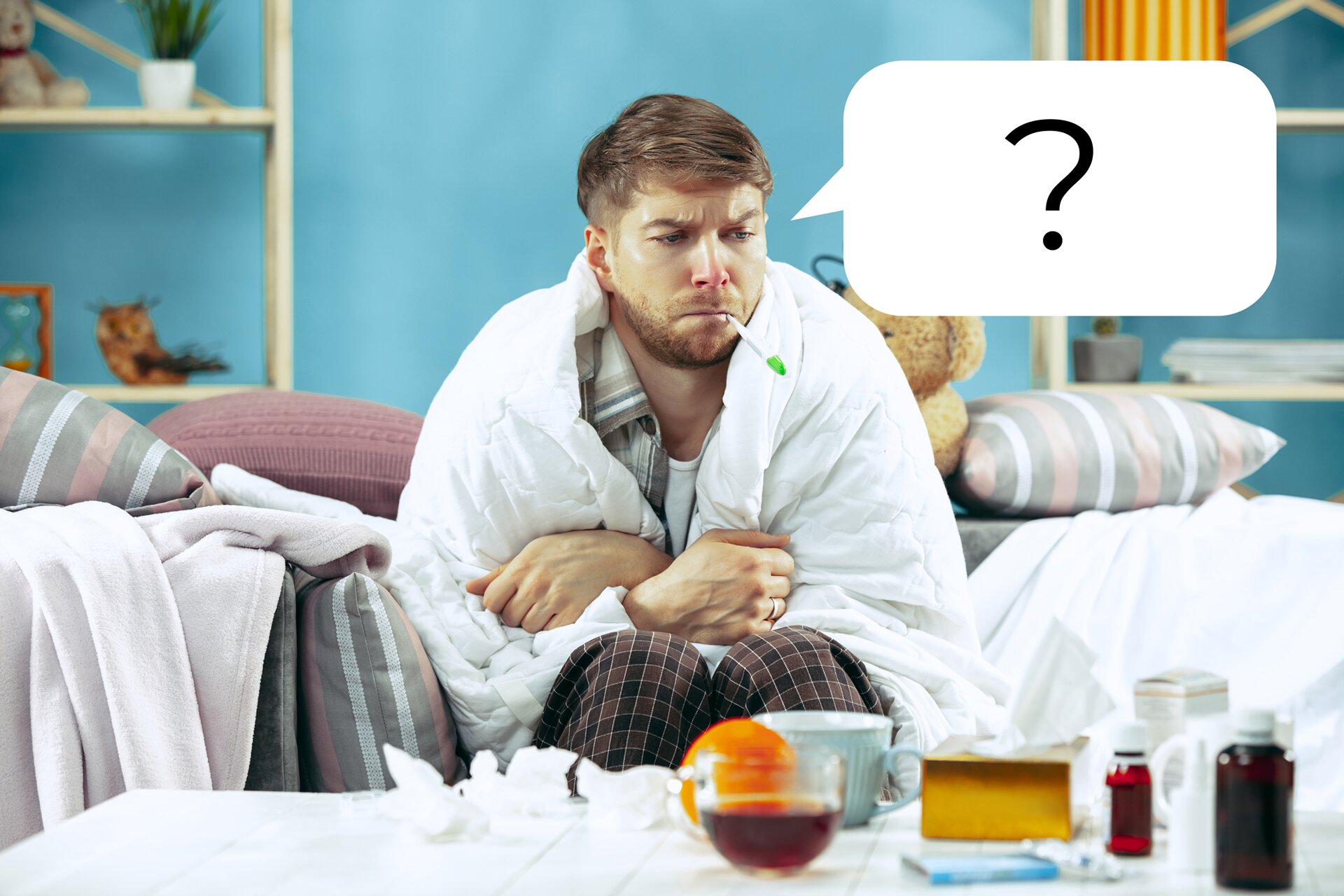 Ilustracja przedstawia mężczyznę siedzącego na kanapie. Nakryty jest kocem i trzyma termometr w ustach. Na stole widoczne są lekarstwa i pudełko chusteczek. Nad jego głową widać chmurkę myślową ze znakiem zapytania. 
