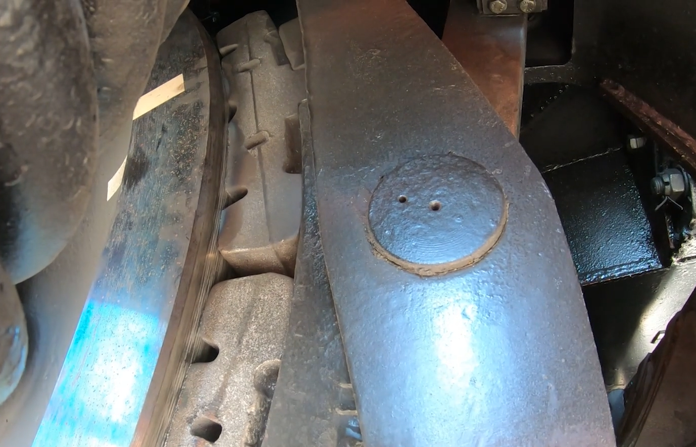 Zdjęcie przedstawia hamulec klockowy. Widoczny jest fragment powierzchni koła oraz dociskane do jego krawędzi dwa bloki.