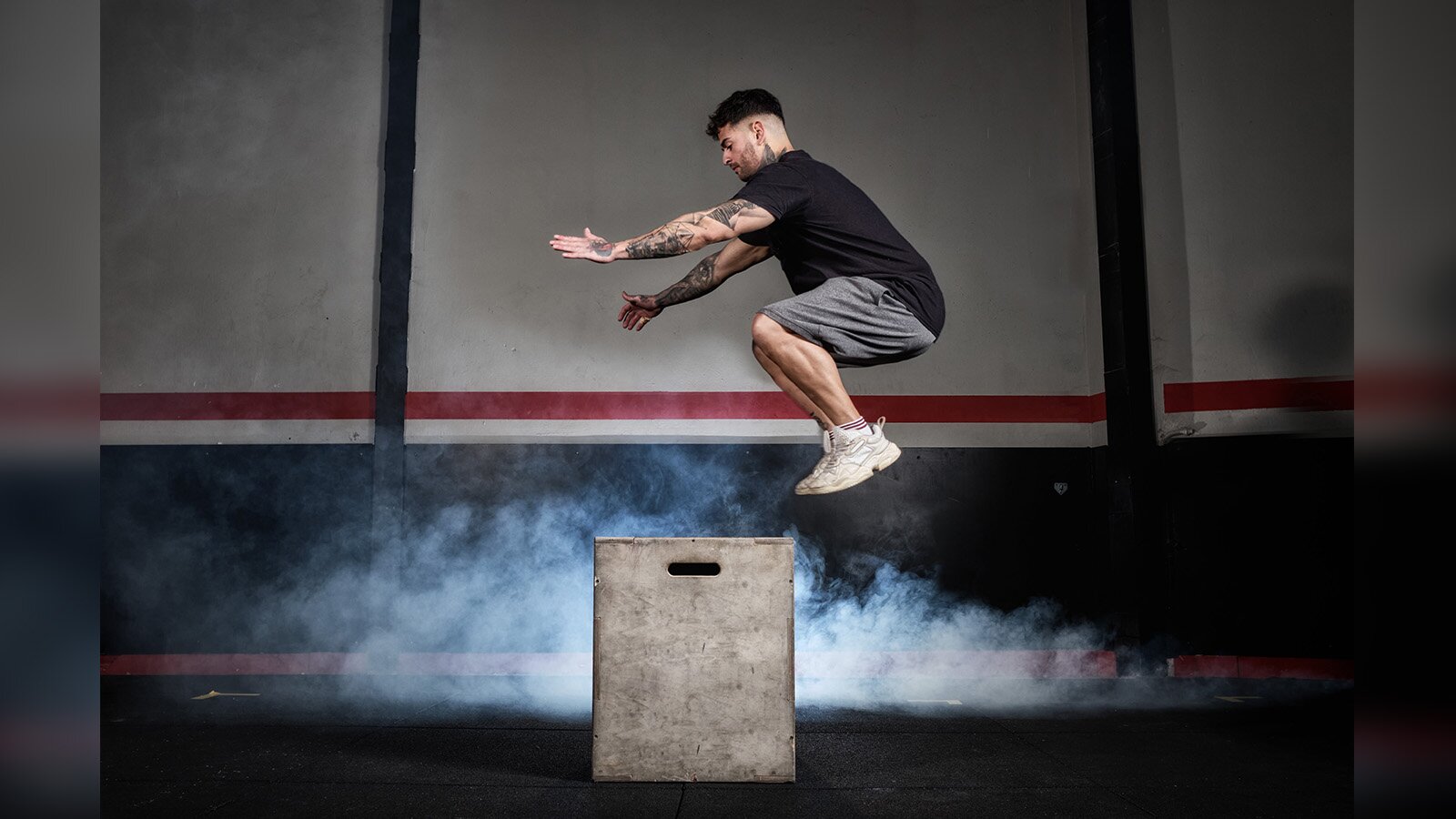Zdjęcie przedstawia mężczyznę przeskakującego przez pudło. 