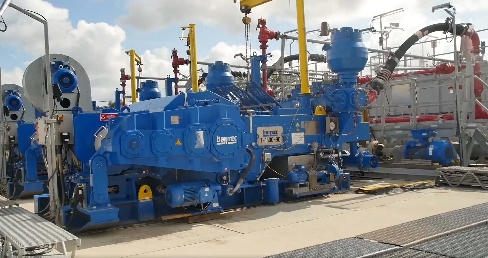 Zdjęcie przedstawia pompę płuczkową czyli odpowiadające za zatłaczanie płuczki wiertniczej na dno otworu z odpowiednio wysokim ciśnieniem pozwalającym na pokonanie oporów przepływu i wyniesienie płuczki z fazą stałą (zwiercinami) na powierzchnię. Pompa płuczkowa jest podłużnym urządzeniem, wykonanym ze stali pomalowanej na kolor niebieski. Do końcówki urządzeina przymocowany jest, gruby elastyczny wąż, który podłączony jest do czerwoego rurociągu. Na zdjęciu widnieje silnik elektryczny napędzający pompę płuczkową, pompa płuczkowa typu triplex wykorzystywana podczas wierceń normalnośrednicowych z prawym obiegiem płuczki wiertniczej. Konstrukcja pompy przewiduje możliwość zamontowania tulei cylindrowych różnych średnic, do pozwala na regulację maksymalnego ciśnienia tłoczenia. Wraz ze wzrostem średnic tulei cylindrowych maksymalne ciśnienie tłoczenia maleje, a strumień objętości rośnie. Strumień objętości pompy jest regulowany również przez zmianę prędkości obrotowej silnika napędzającego pompę oraz odśrodkowa pompa doładowująca ssąco‑tłocząca.