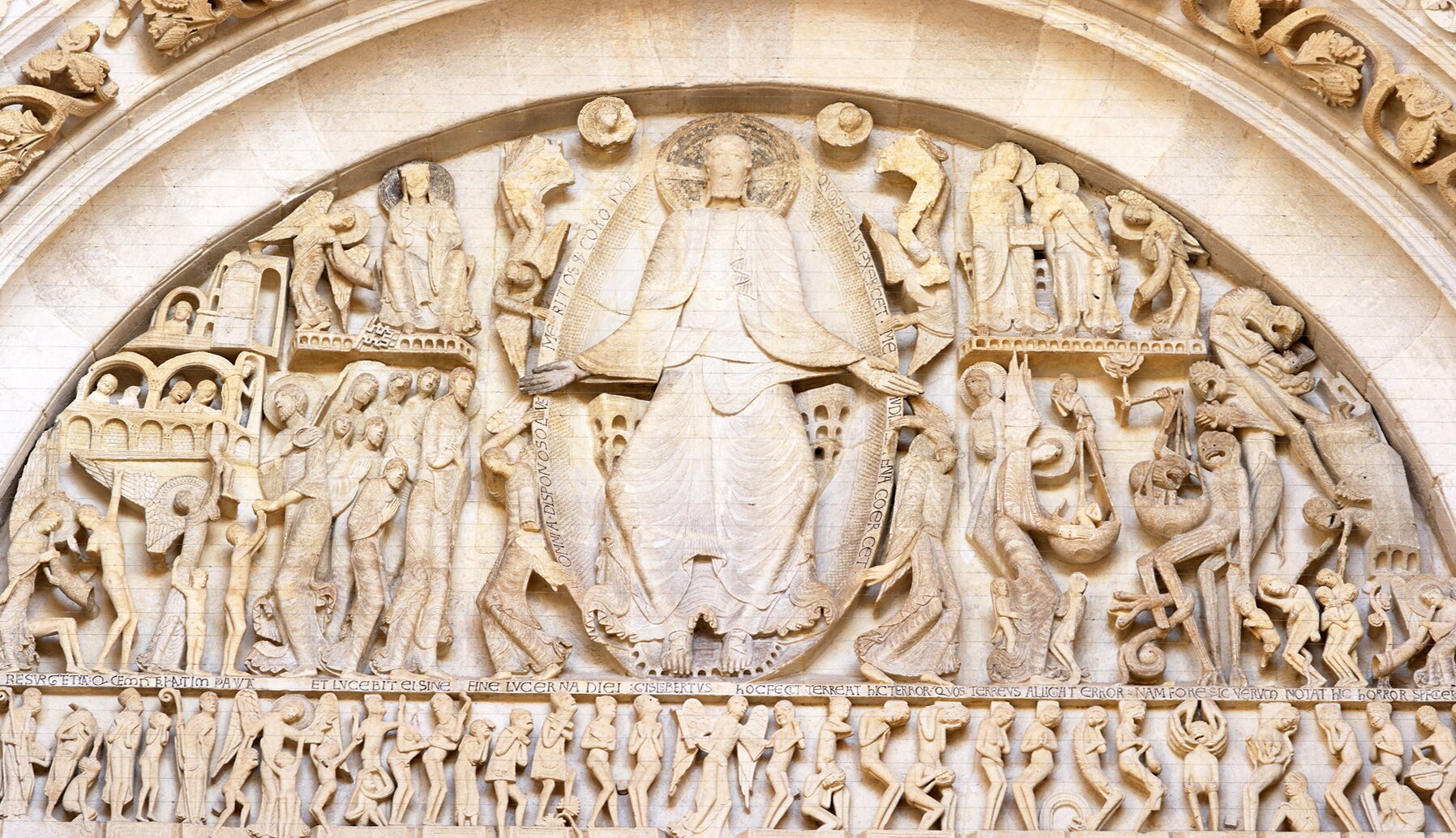 Na zdjęciu znajduje się płaskorzeźba przedstawiająca  scenę Sądu Ostatecznego. W centrum znajduje się Jezus w mandorli z łacińskimi sentencjami. Rozkłada ręce i unosi delikatnie do góry. Na jego głowie znajduje się aureola. Jest ubrany w długą szatę. Siedzi na tronie. Całość podtrzymują cztery anioły, nad którymi górują przedstawienia słońca i księżyca.  Po Jego prawicy dostrzec można dziewięciu apostołów ze świętym Piotrem na czele spoglądającym w niebo zobrazowanym  przy pomocy arkad. W  niebie znajduje się Matka Boża siedząca  na tronie w towarzystwie grającego anioła.  Pod stopami Jezusa widać napis: Gislebertus hoc fecit wskazujący na autora dzieła. Po lewej stronie rozgrywa się scena piekła, w której został umieszczony Archanioł Michał ważący dusze. W jego otoczeniu umieszczono lewiatana, szatana oraz kilku potępieńców pożeranych przez diabły czy gotowanych w kotle. W nadprożu widzimy natomiast zmartwychwstanie umarłych podzielonych według hierarchii. Po prawej stronie   znajdują się dzieci, pielgrzymi, ludzie kościoła, zaś po lewej niegodziwcy. 