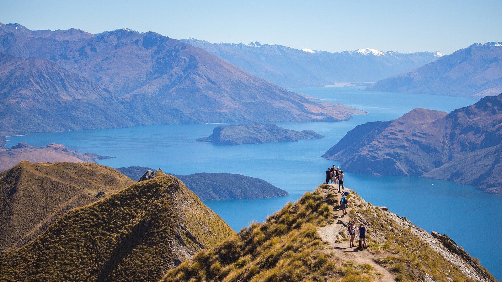 Zdjęcie przedstawia pagórki usytuowane w wodzie. Na jednym z nich widoczna grupka osób. 