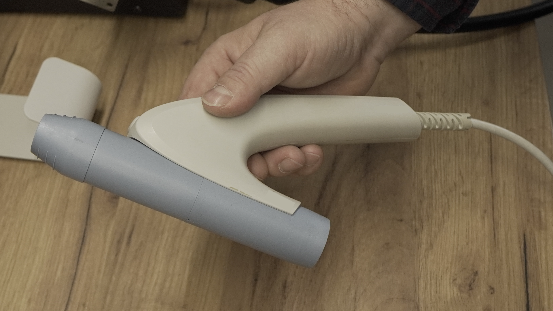 Zdjęcie przedstawia przetwornik spirometru trzymany przez technika w dłoni.