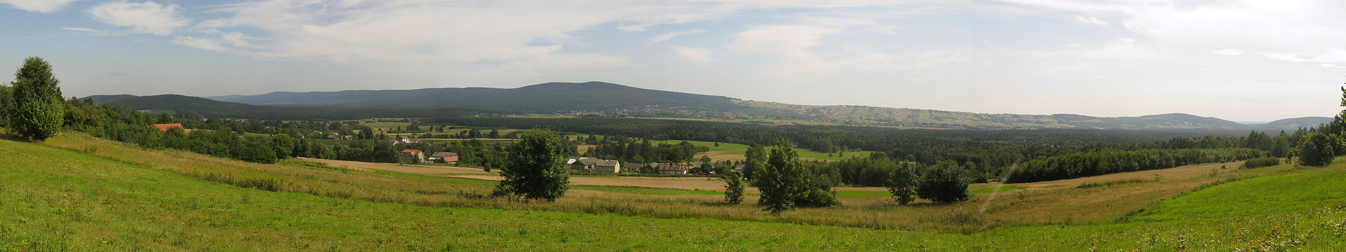 Druga fotografia , to krajobraz Gór Świętokrzyskich, widoczny teren falisty porośnięty trawą.