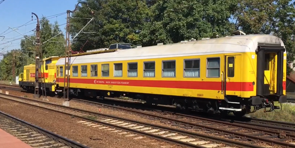 Ilustracja przedstawia żółty wagon pomiarowo diagnostyczny.