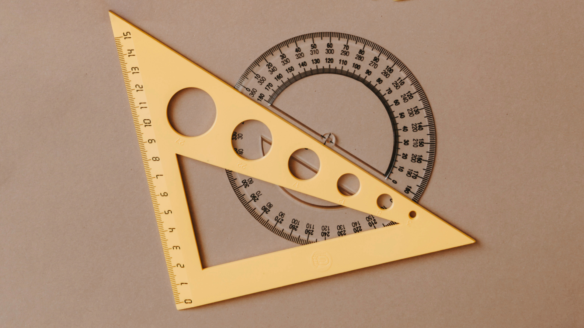 Zdjęcie przedstawia ekierkę leżącą na kątomierzu. 