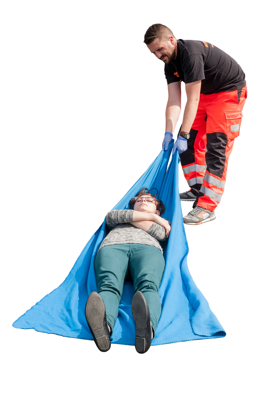 Na ilustracji numer pięć ratownik ubrany w pomarańczowo czarne spodnie z paskami odblaskowymi poniżej kolan ciągnie poszkodowaną kobietę ułożoną na niebieskiej tkaninie. Kobieta leży na plecach, ręce ma złożone na klatce piersiowej.