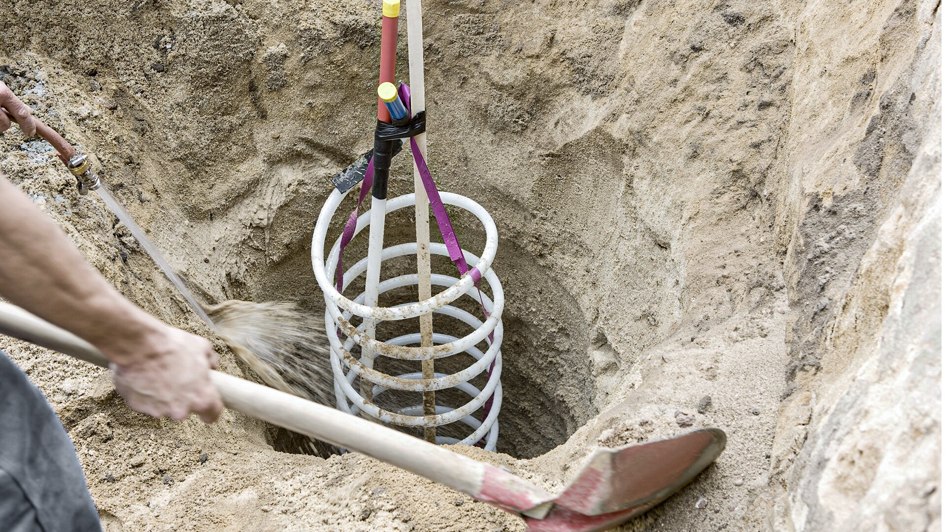 Zdjęcie przedstawia kolektor spiralny umieszczony w wywierconym w glebie otworze. Kolektor ma postać cienkiej rurki wykonanej z tworzywa sztucznego, uformowanej w długą spiralę.