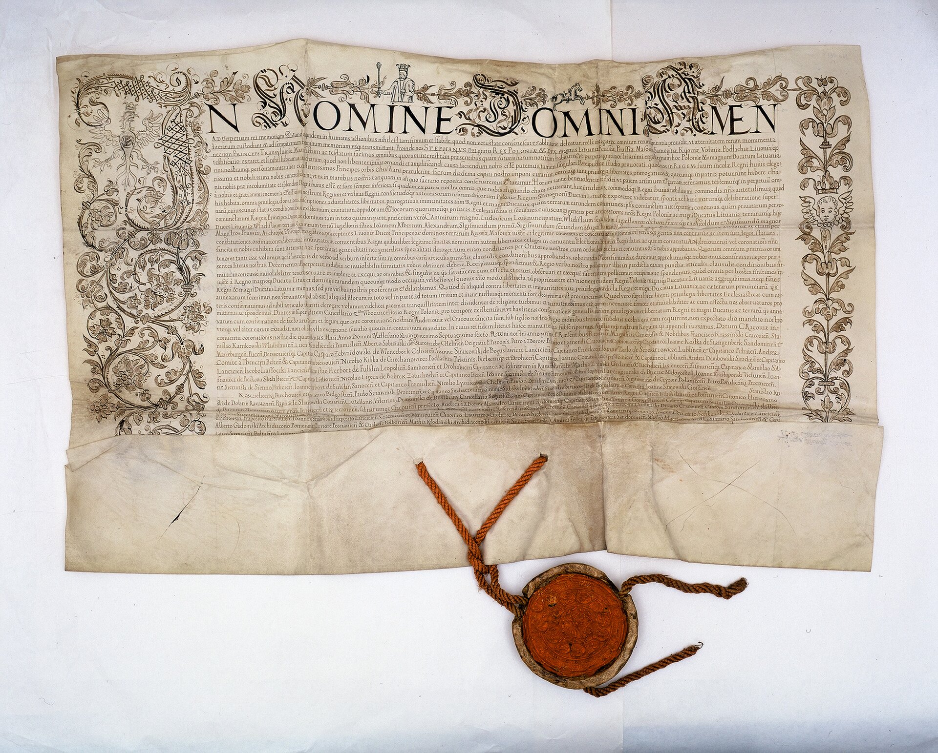 Zdjęcie przedstawia dużą kartę z tekstem, ozdobioną roślinnym ornamentem na marginesach. Na dole karty znajduje się duża, woskowa, okrągła pieczęć.