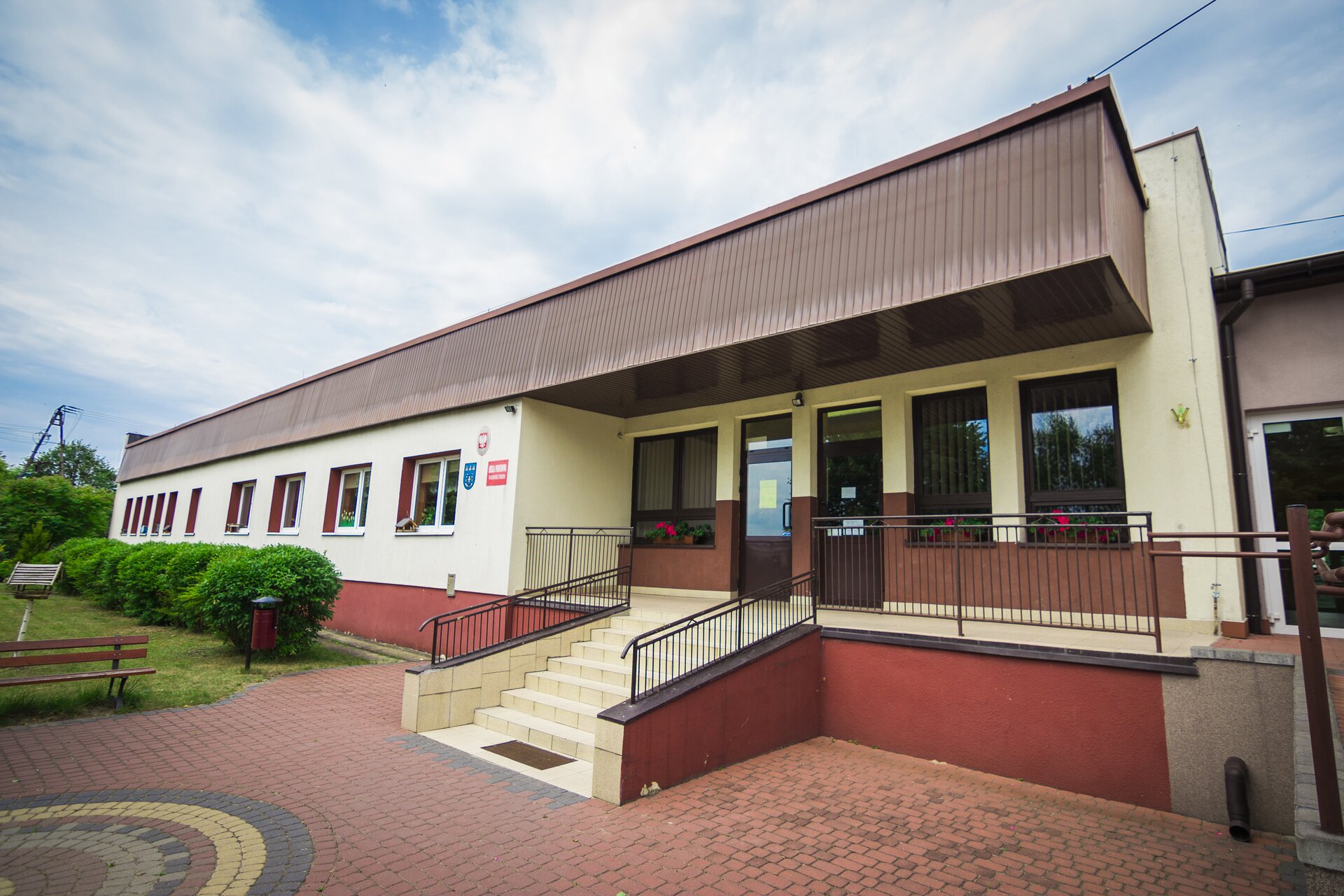 Zdjęcie przedstawiające budynek szkoły podstawowej w miejscowości Annopole Stare. Stoi na czerwonej podbudówce, jest parterowy. Prowadzą do niego schody.