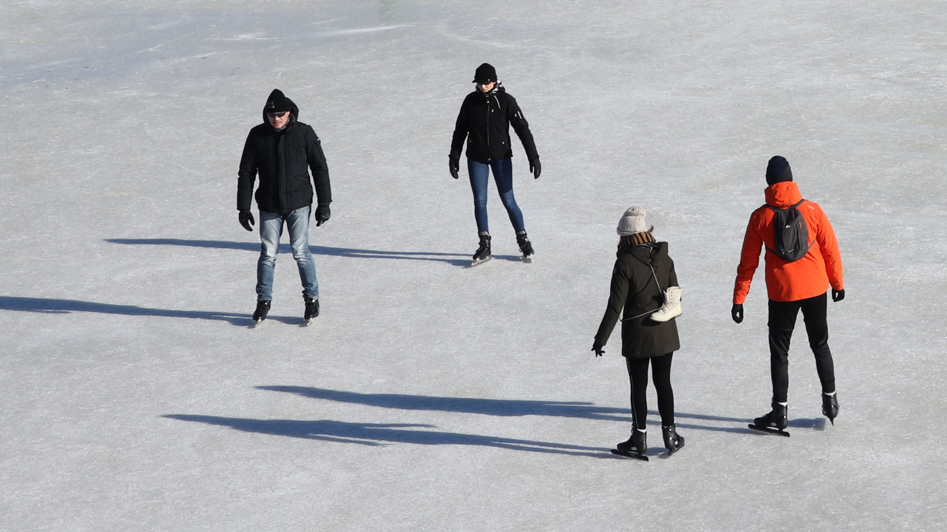 Zdjęcie przedstawia cztery osoby jeżdżące na łyżwach po lodzie.