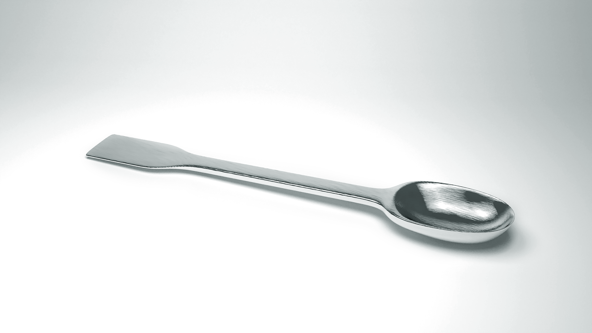 Zdjęcie przedstawiające łyżkę laboratoryjną, to jest długi metalowy trzonek z jednej strony zakończony łyżką, a z drugiej łopatką.