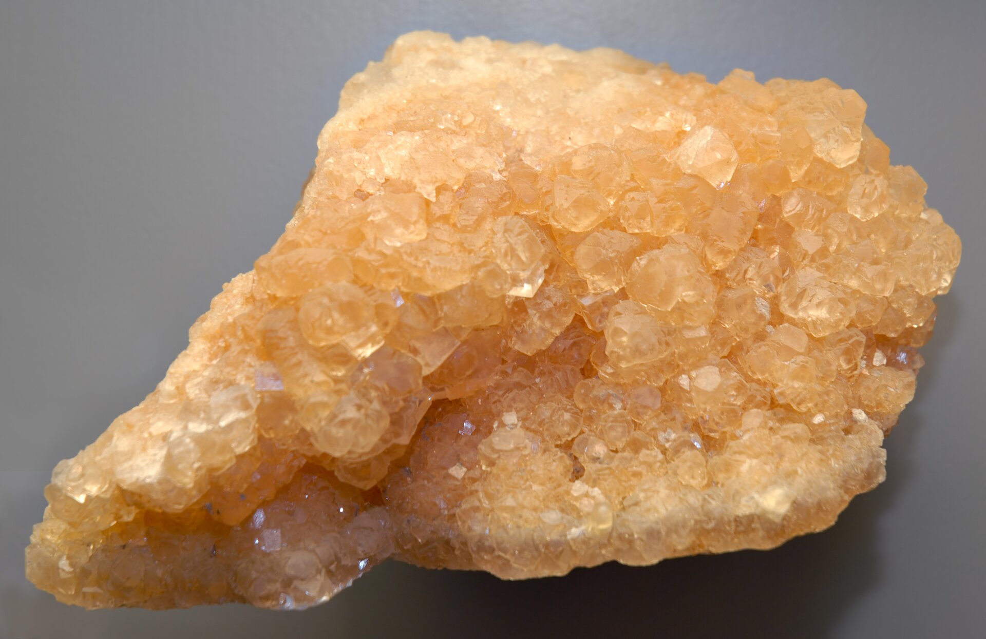 Zdjęcie przedstawiające kryształy sylwinu. Przezroczysty jasnopomarańczowy minerał ma nieregularną kształt. 