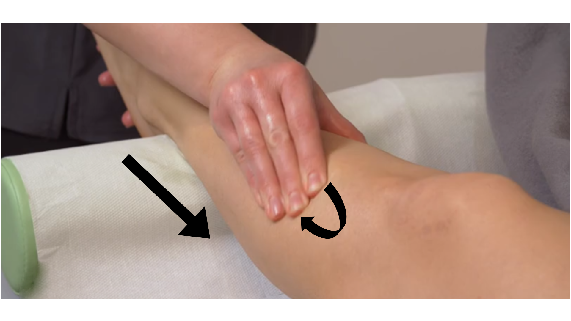 Zdjęcie pod tytułem rozcieranie przednio‑bocznej strony podudzia. Na zdjęciu masażystka podtrzymuje jedną ręką stopę pacjentki podpartą wałkiem. Druga ręka masażystki rozciera rejon podudzia pacjentki przy użyciu opuszków palców.