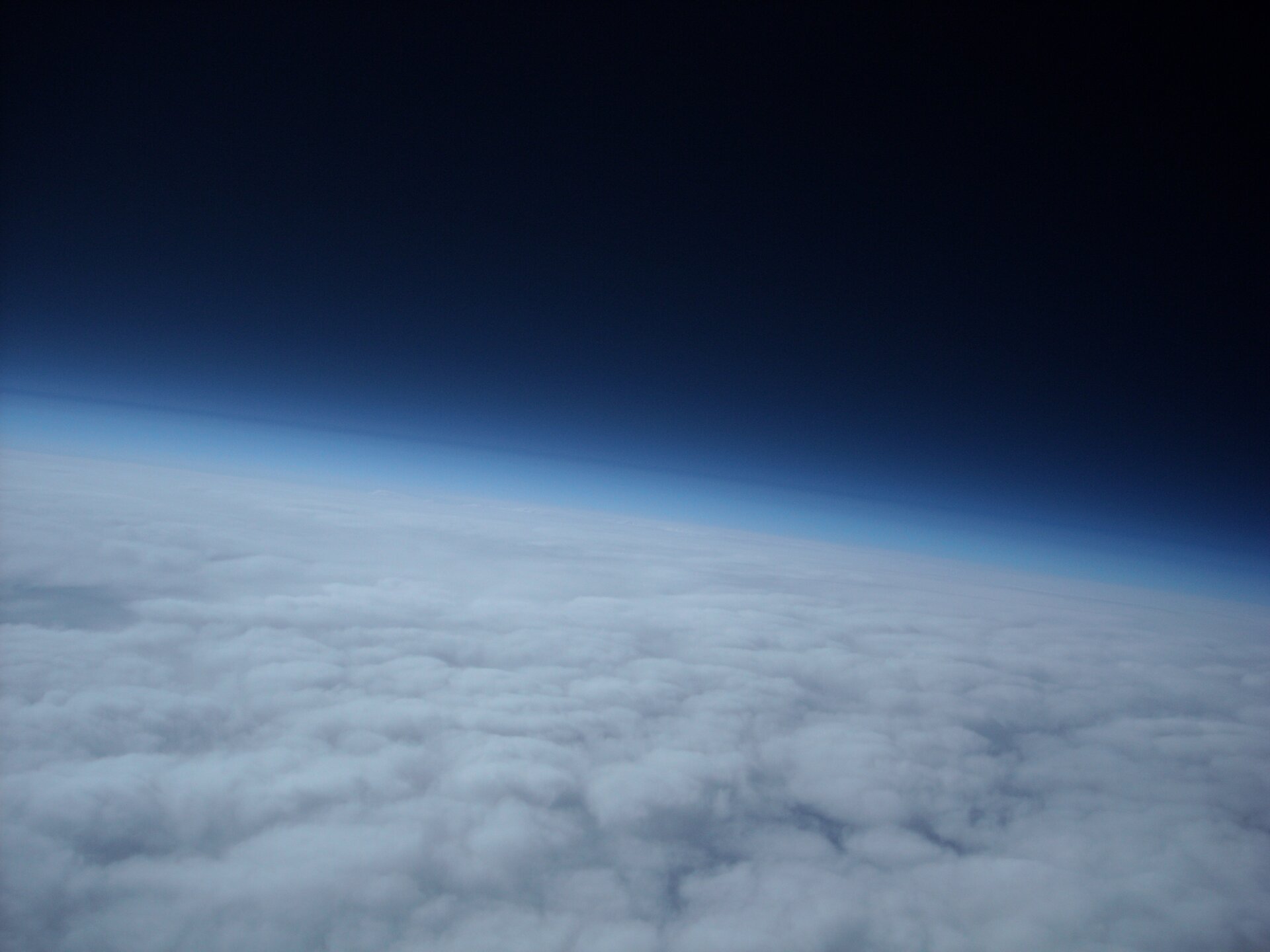 Zdjęcie przedstawia atmosferę ziemską. Na zdjęciu widoczna jest planeta Ziemia z kosmosu?. Jest ona otoczona jasną/jasnoniebieską? gazową powłoką.