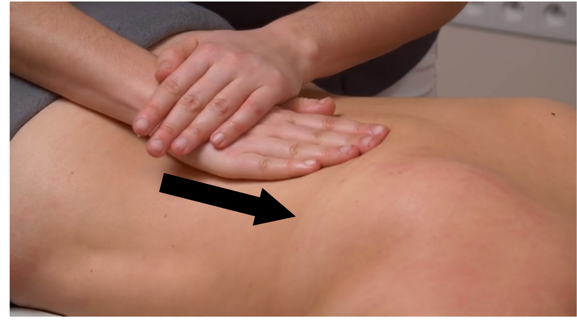 Zdjęcie pod tytułem wibracja mięśni przykręgosłupowych i mięśni grzbietu. Zdjęcie przedstawia rękę masażystki wykonującą technikę wibracji poprzez ułożenie powierzchni dłoniowej ręki do powierzchni mięśni grzbietu po stronie prawej i przesunięcie jej od odcinka lędźwiowego w kierunku odcinka szyjnego przykręgosłupowo.