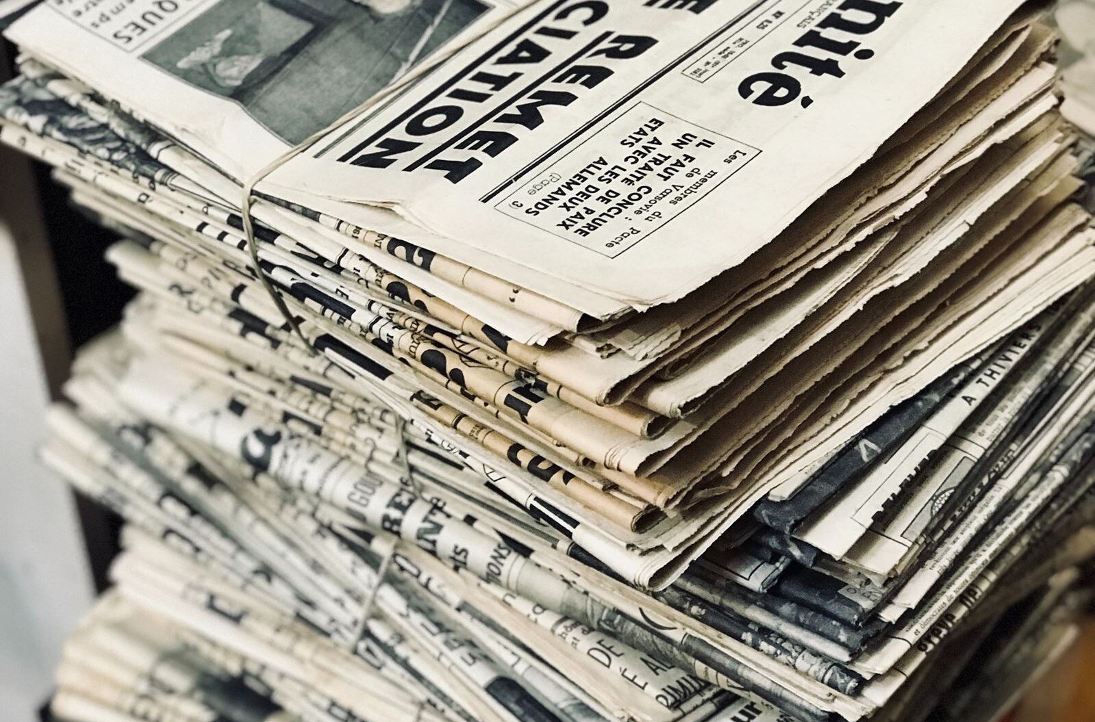 Zdjęcie przedstawia stos gazet związanych sznurkiem w paczki po kilka sztuk.