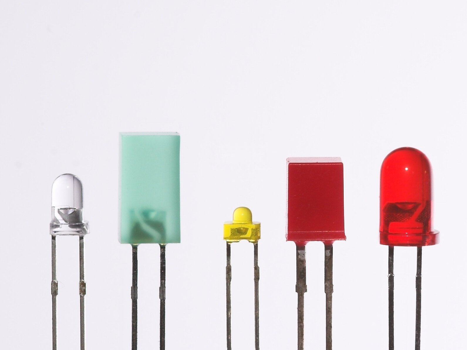 Ilustracja przedstawia kolorowe diody. Są to pręciki, na którym znajdują się nasadki o kształcie prostokątnym bądź zaokrąglonym. Diody mają kolory: biały, żółty, błękitny i czerwony.