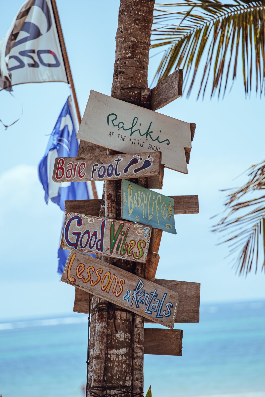 Fotografia słupka, na którym umieszczono drewniane tabliczki z oznaczeniami miejscowości lub hasłami w języku angielskim.