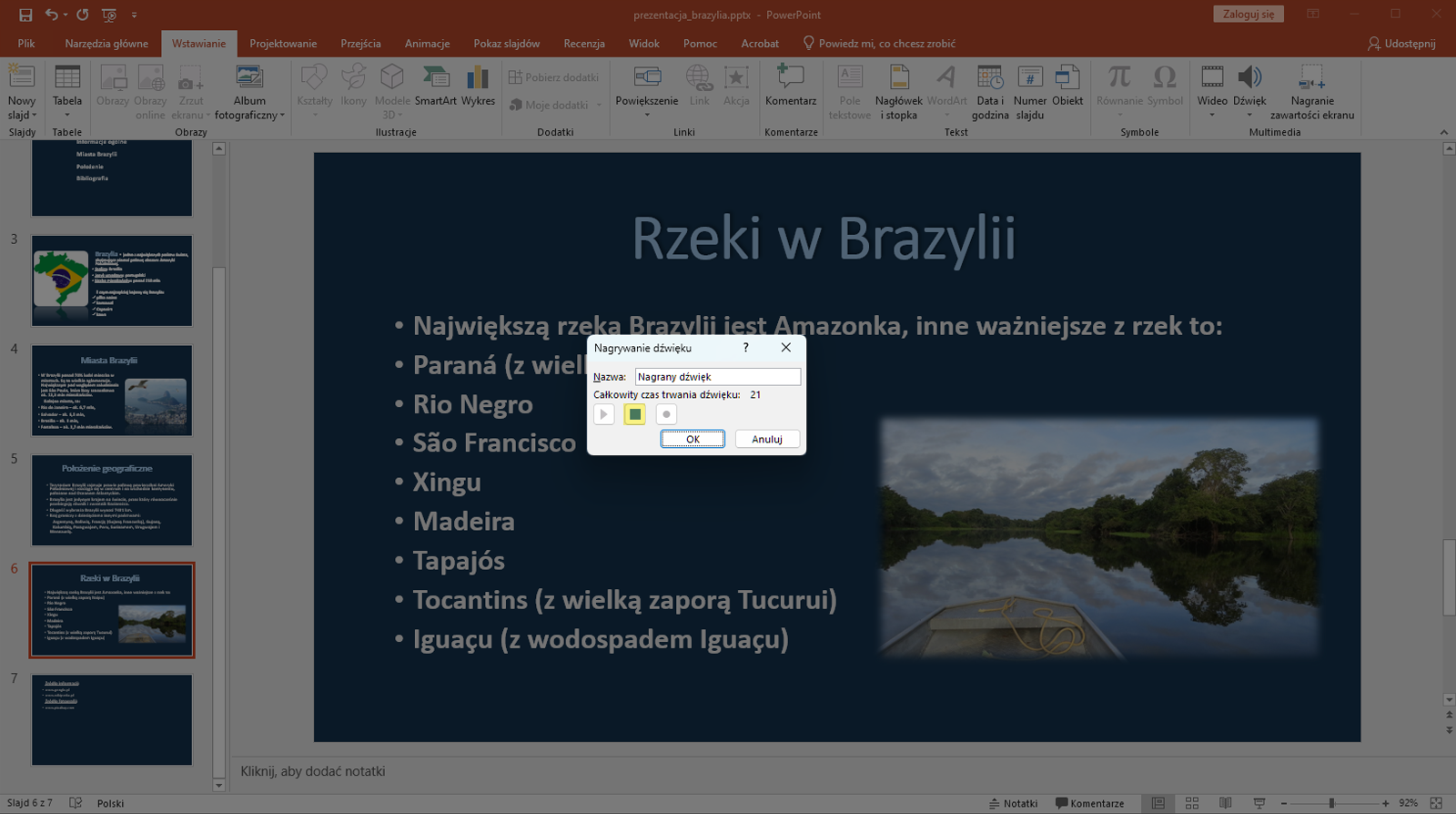 Zrzut ekranu przedstawia wycinek okna programu Microsoft PowerPoint. Prezentacja zapisana jest jako prezentacja brazylia.pttx. W programie znajdują się zakładki takie jak „Plik”, „Narzędzie główne”, „Wstawianie”, „Projektowanie”, „Przejścia”, Animacje”, „Pokaz slajdów”. Recenzje”, „Widok”, „Pomoc”, „Acrobat” oraz „Powiedz mi, co chcesz zrobić”.  Po lewej stronie znajduje się lista slajdów. Prezentacja składa się aktualnie z siedmiu slajdów. Wybrano slajd szósty. Na większości okna programu znajduje się powiększony slajd szósty o nazwie Rzeki w Brazylii. Na slajdzie zapisano nazwy rzek w Brazylii. Pod slajdem znajduje się miejsce na notatkę. Całe okno prezentacji jest wyciemnione. Pojawia się okno „ Nagrywanie dźwięku” na środku okna prezentacji. W oknie wpisano nazwę dźwięku – Nagrany dźwięk. Pod spodem zapisano Całkowity czas trwania dźwięku dwadzieścia jeden. Pod spodem znajdują się trzy kwadratowe przyciski, jeden obok drugiego kolejno plej, stop, nagrywanie. Przycisk nagrywania to czerwona kropka na środku kwadratu.  Wciśnięto przycisk stop. W prawym dolnym rogu znajduje się przycisk ok oraz anuluj. Podświetlono przycisk okej. 