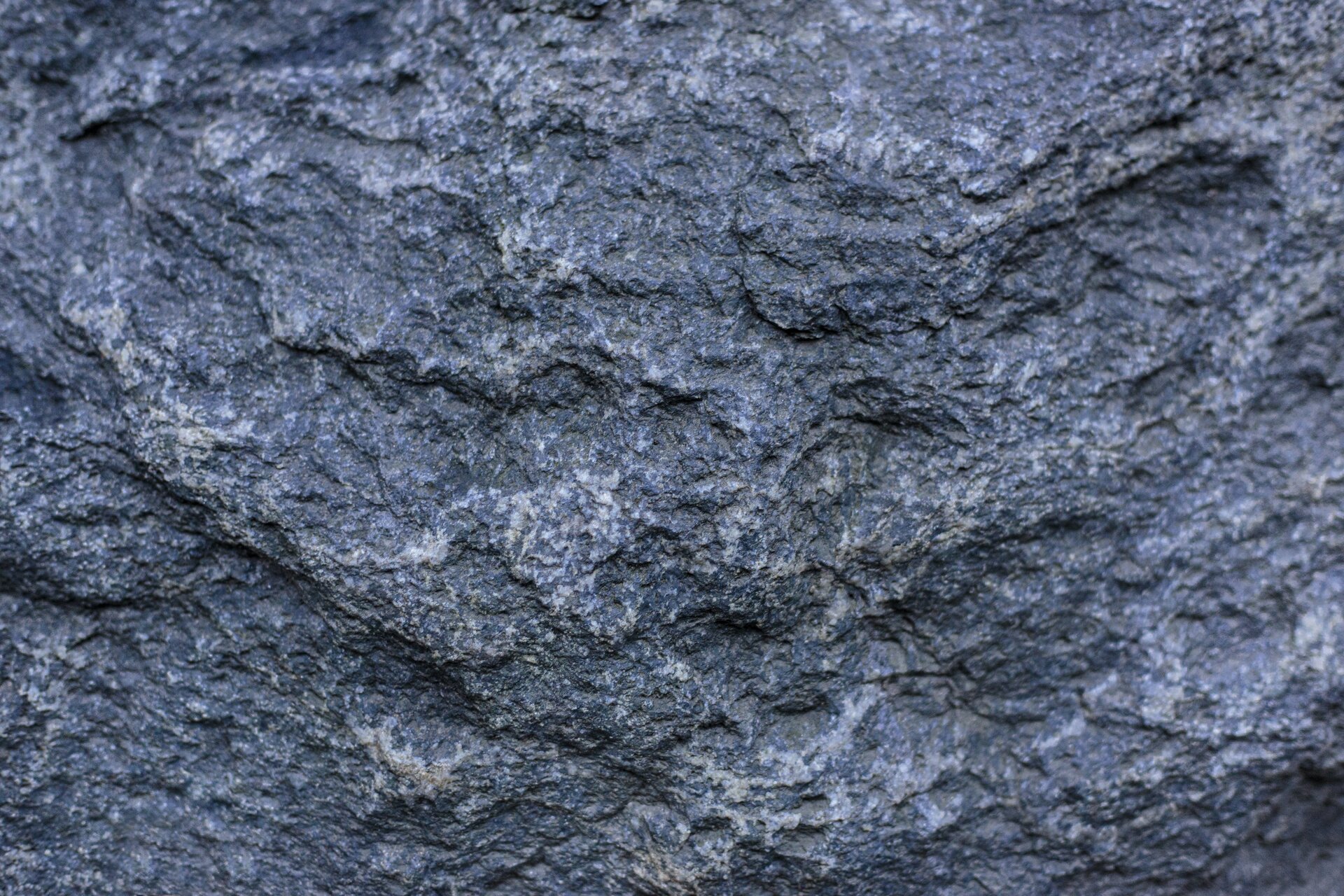 Zdjęcie przedstawia nierówną, chropowatą fakturę ciemnogranatowego kamienia przed groszkowaniem.