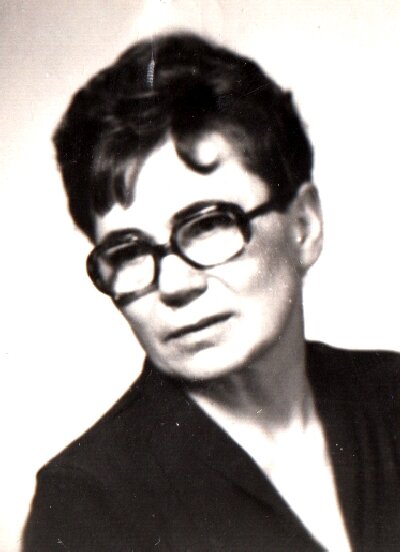 Zdjęcie przedstawia kobietę o twarzy z mocno zarysowaną linią szczęki, krótkich włosach oraz okularach w dużych oprawkach.