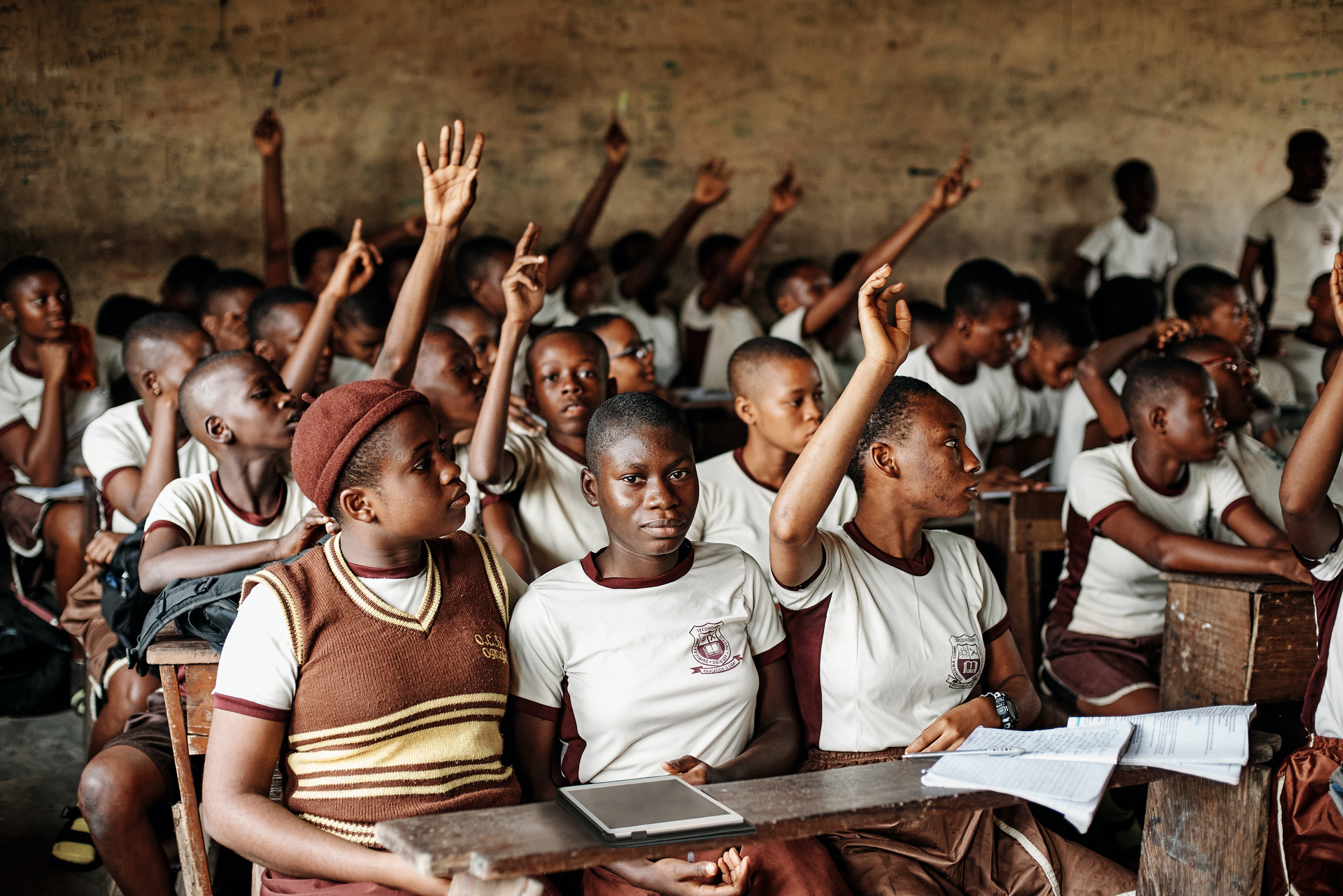Na drugiej ilustracji ukazana jest grupa młodzieży o ciemnym kolorze skóry. Zajmują oni miejsca na krzesłach w pomieszczeniu, przed sobą mają niewielkie ławki z zeszytami. Kilka osób wśród nich podnosi rękę.