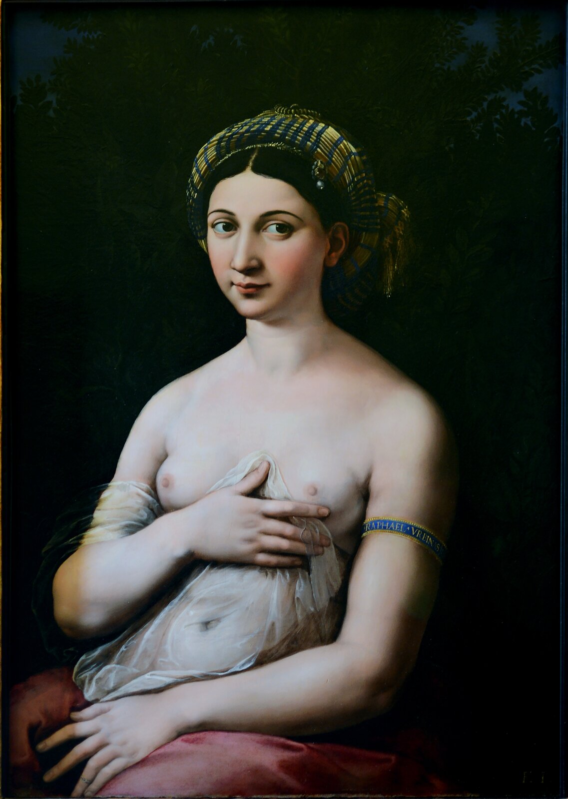 Ilustracja przedstawia portret młodej kobiety. Postać ukazuje lewy półprofil. Twarz kobiety jest okrągła. Jej czoło jest gładkie, brwi ciemne, a oczy duże. Patrzy w swoją lewą stronę. Kobieta ma długi, prosty nos, zarumienione policzki i duże usta z uniesionymi kącikami. Włosy postaci są ciemne, równo zaczesane na obie strony i związane z tyłu głowy. Głowa jest okręcona wąską apaszką pasiastym wzorem. Postać ukazuje nagie piersi. Są małe. Jej brzuch okrywa przezroczysta tkanina. Na nogach kobiety leży błyszcząca tkanina.