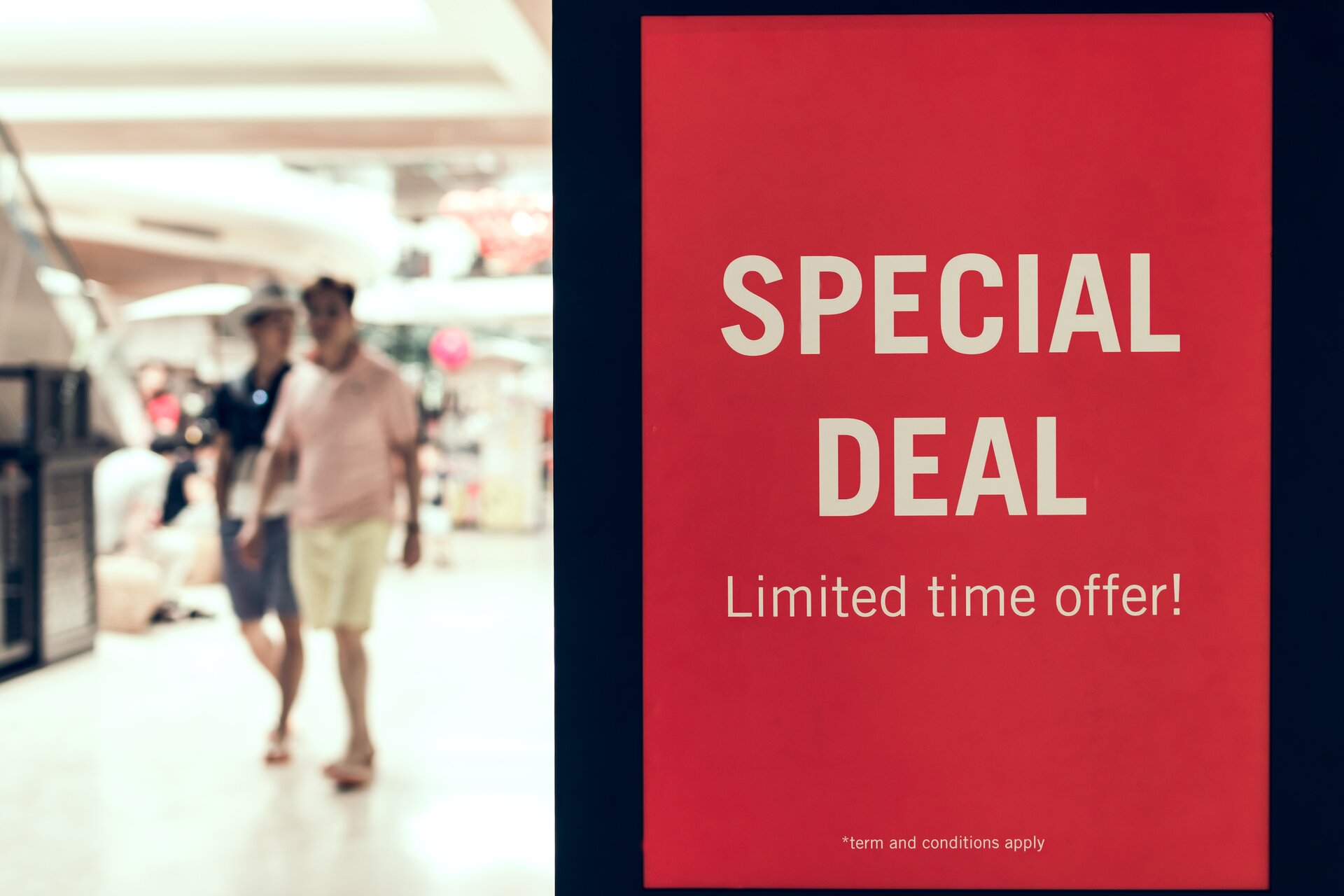 Fotografia przedstawia dwie osoby spacerujące po centrum handlowym. Po prawej stronie widać napis: Special deal, limited time offer – Wyjątkowa okazja, oferta ograniczona czasowo.