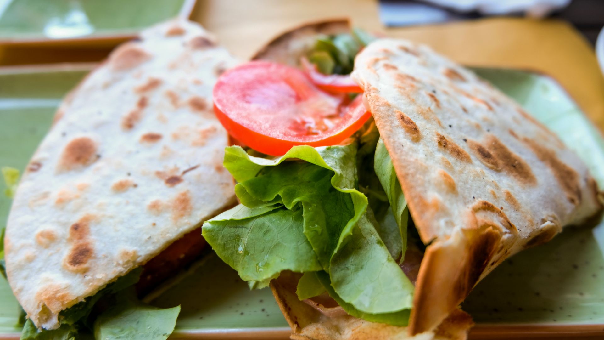 Zdjęcie przedstawia cienkie placki z nadzieniem. Widoczny jest także plaster pomidora oraz liść sałaty.