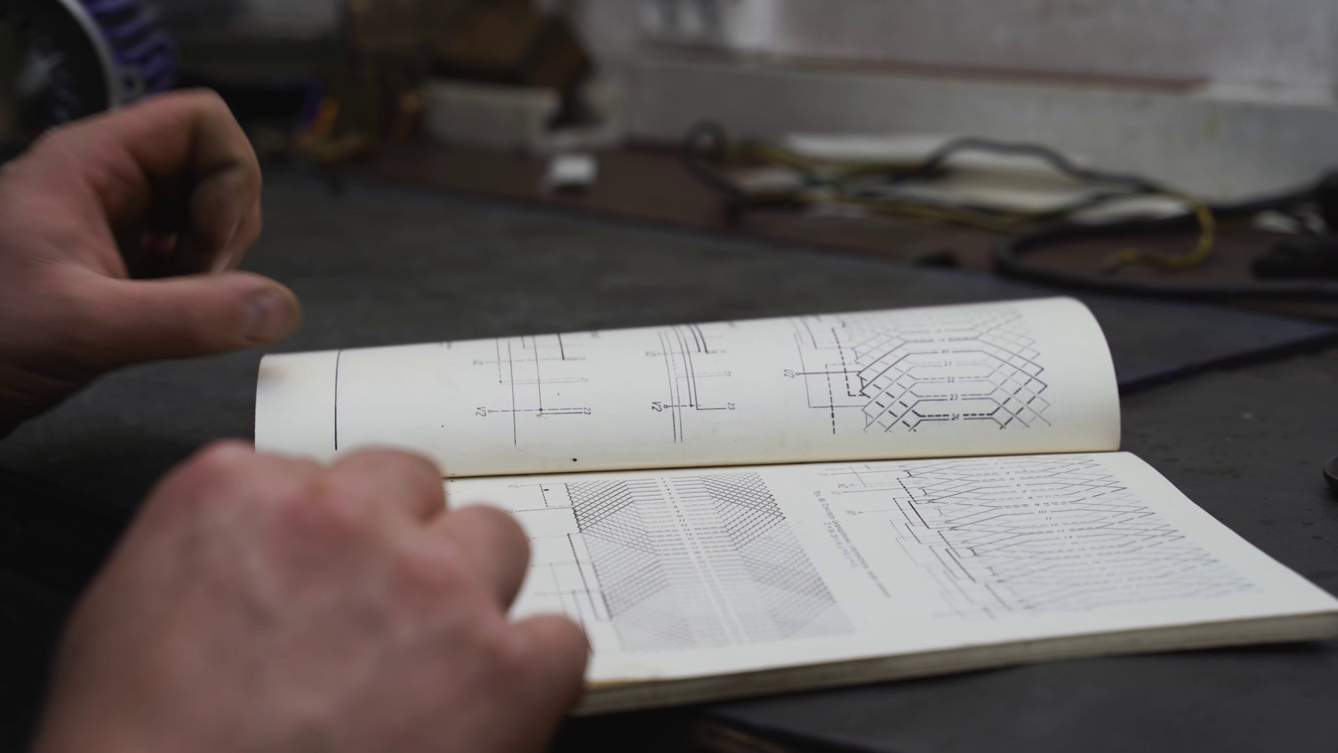 Zdjęcie przedstawia zbliżenie na książkę ze schematami, która przegląda elektromechanik.