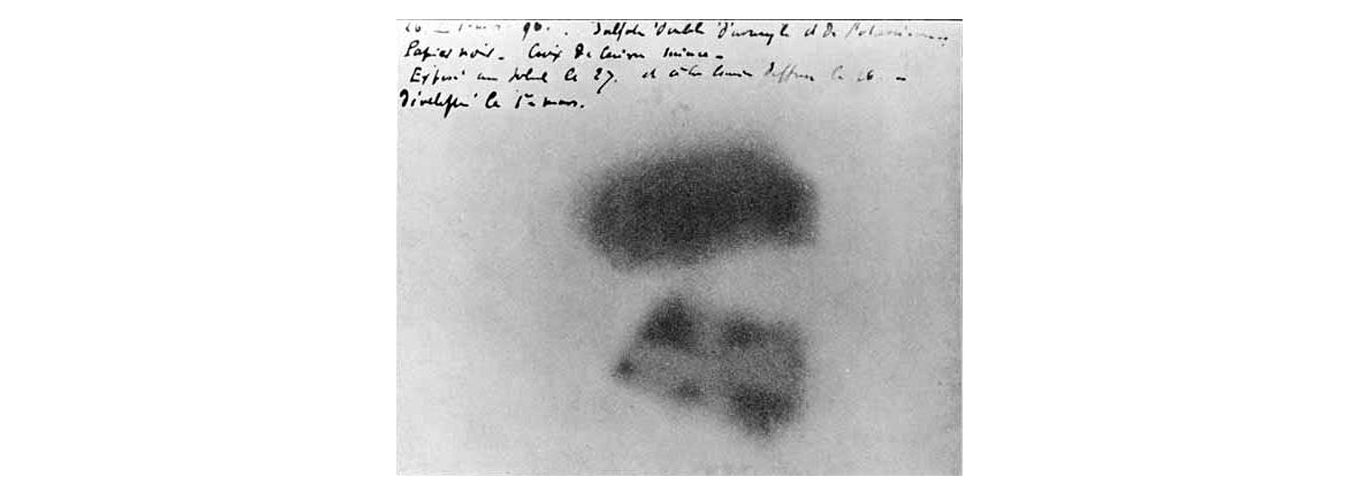 Ilustracja przedstawia kliszę naświetloną przez Becquerela. Klisza to jasnoszary obszar stanowiący tło, z widocznymi dwoma ciemnoszarymi plamami po środku. Plamy przypominają dwa prostokąty leżące jeden nad drugim.