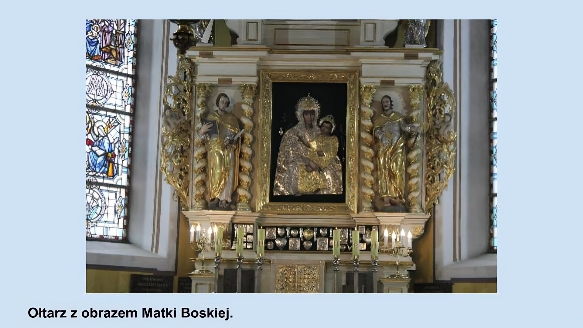 Ilustracja przedstawia ołtarz z obrazem Matki Boskiej. W centrum ołtarza obraz - Matka Boska w złotej koronie i srebrnych szatach trzyma na rękach postać  małego Jezusa w złotej koronie i w złotej szacie, na około nich srebrzyste poświaty. Z tyłu czerwone tło. Obraz w rzeźbionej, złotej ramie. Po bokach postacie dwóch świętych w złotych szatach. pod ołtarzem dwa świeczniki, w każdym trzy żółte świece.