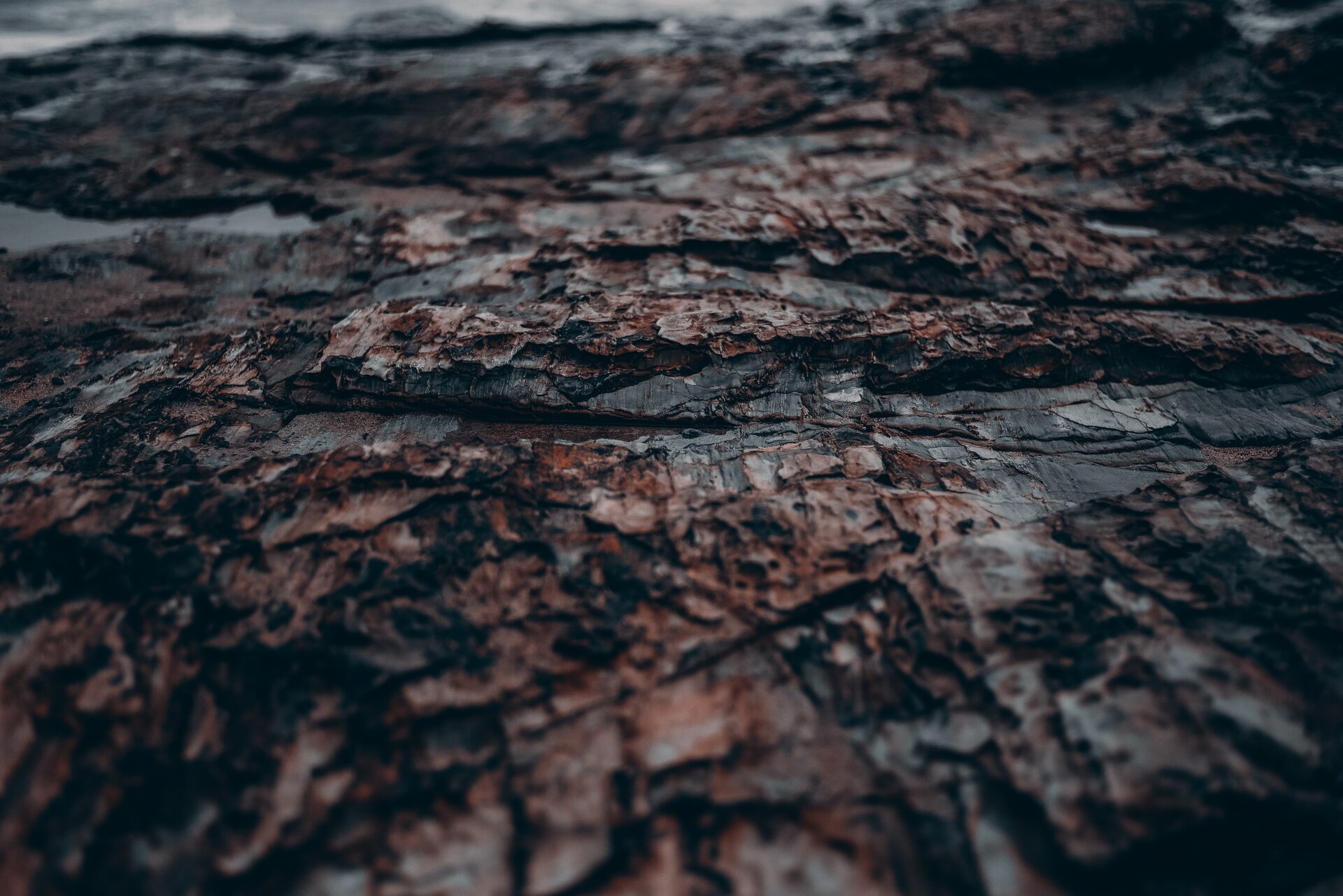 Zdjęcie przedstawia chropowatą, nieregularną powierzchnię kamienia przed polerowaniem. Widoczne są liczne rysy oraz zmiany w fakturze materiału.