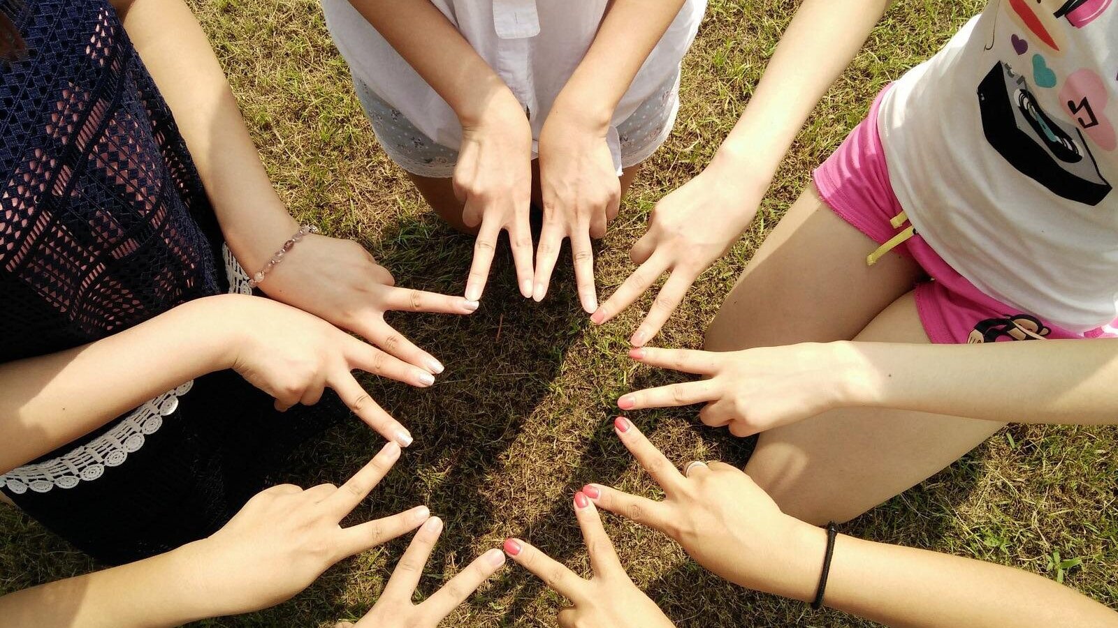 Na ilustracji obserwujemy pięć młodych osób, które łączą ze sobą palce wskazujące i środkowe obu dłoni, tworząc tym samym niezwykły kształt przypominający gwiazdę.

