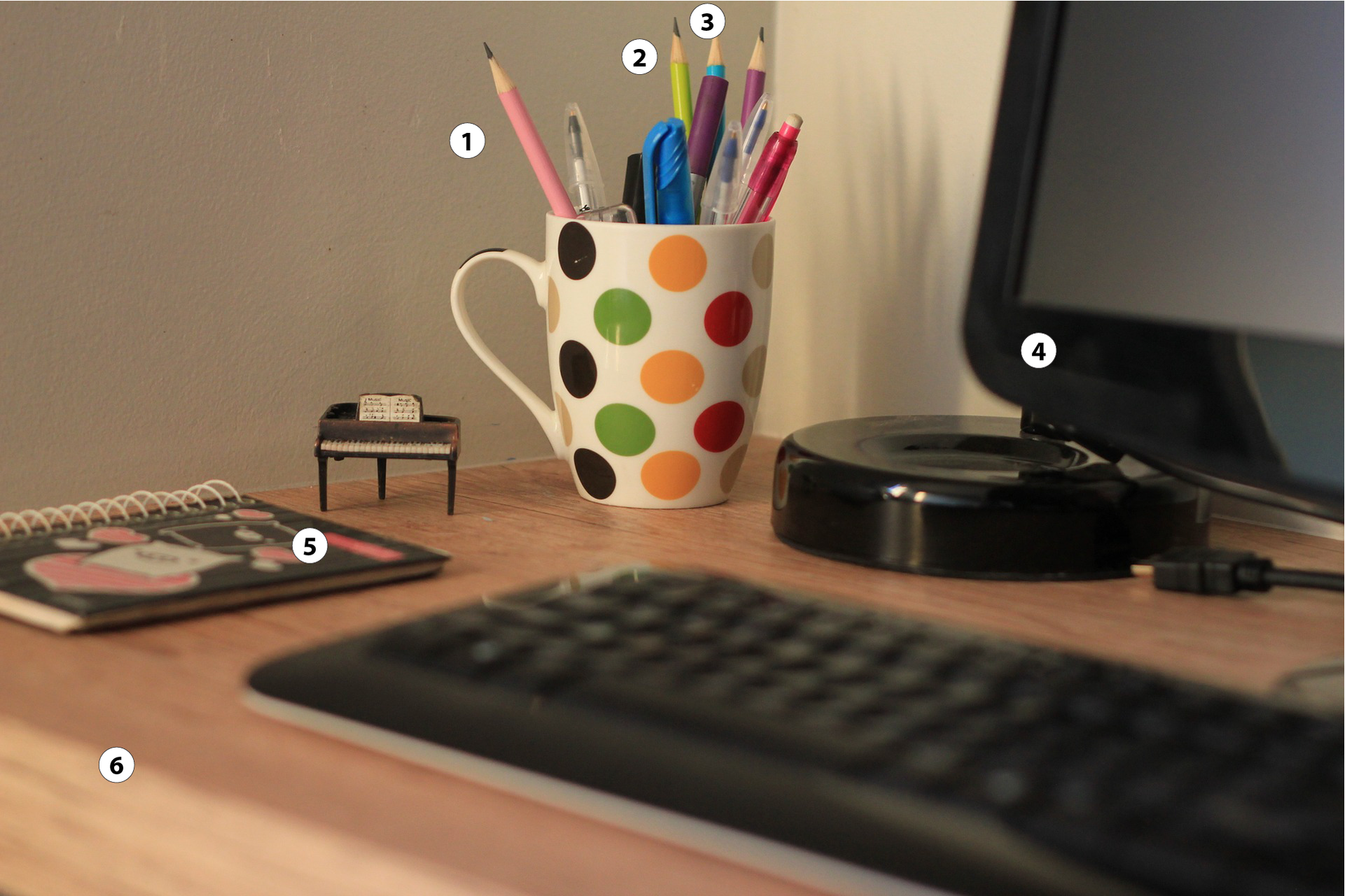 Ilustracja przedstawia biurko. Jeden. Różowy ołówek. Dwa. Żółty ołówek. Trzy. Niebieski ołówek. Cztery. Czarny komputer. Pięć. Kolorowy zeszyt. Sześć. Brązowe biurko
