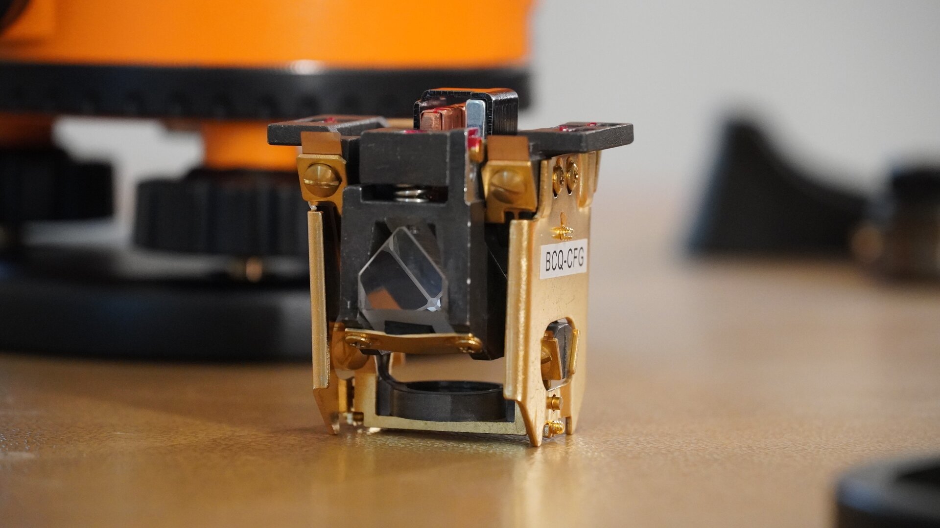 Na zdjęciu ukazano zbliżenie mechanizmu kompensatora. W dolnej części znajduje się wahadło, które jest wprawiane w ruch dzięki magnesowi umieszczonemu na dole mechanizmu. Do wahadła przymocowane jest szkiełko pryzmatu łamiącego. Cały mechanizm wahadła jest podtrzymywany przez nici stalowe.