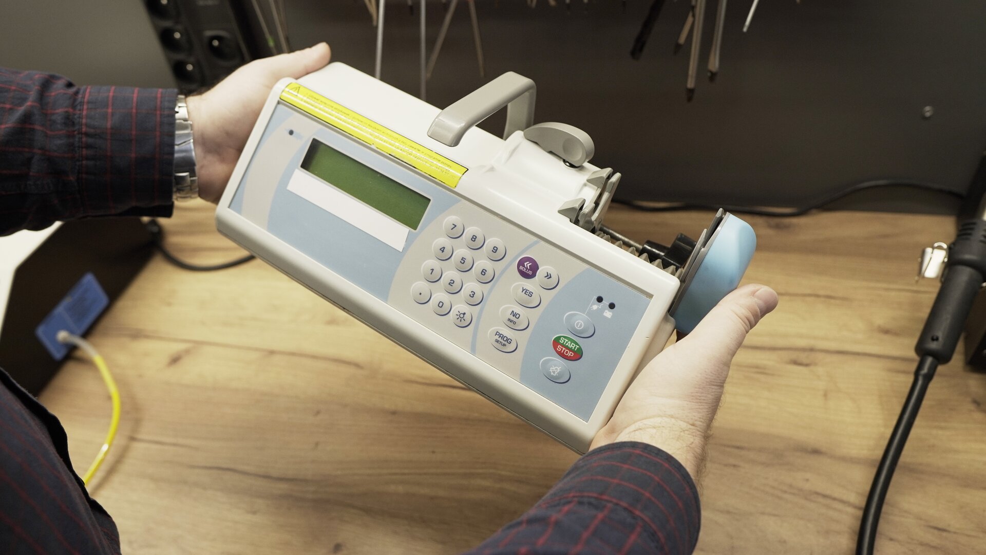 Na zdjęciu technik przeprowadza test wizualny pompy infuzyjnej. Ogląda panel przedni aparatu.  