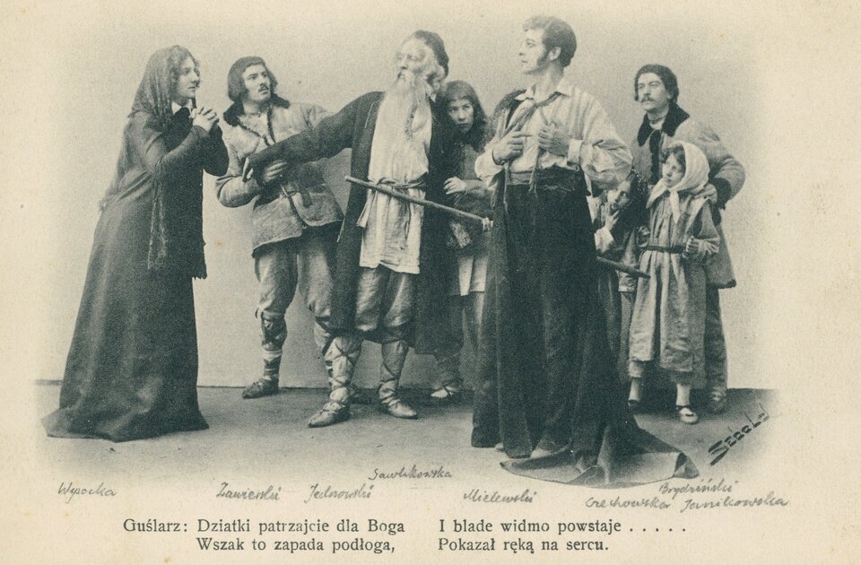 Zdjęcie przedstawia scenę z  II części „Dziadów"  Adama Mickiewicza – pojawienie się ostatniego ducha – Upiora. Kilku ludzi z pospólstwa przygląda się kobiecie i mężczyźnie. Jednym z nich jest Guślarz, postać, która przewodniczyła obrzędowi dziadów. Człowiek ten wyróżnia się starszym, niż pozostali, wiekiem i długą brodą. Dwoje wpatrujących się w siebie ludzi – kobieta i mężczyzna – nie widzi poza sobą świata. Ona składa ręce jak do modlitwy, on jest duchem przybyłym na dziady, by spotkać się z dawną ukochaną. Trzyma ręce na sercu. Na dole zdjęcia widoczny jest fragment z dramatu: Guślarz: Dziatki patrzajcie na Boga / Wszak to zapada podłoga, / I blade widmo powstaje… / Pokazał ręką na serce. Powyżej tego tekstu są wypisane nazwiska aktorów grających w spektaklu "Dziadów" poszczególne role.