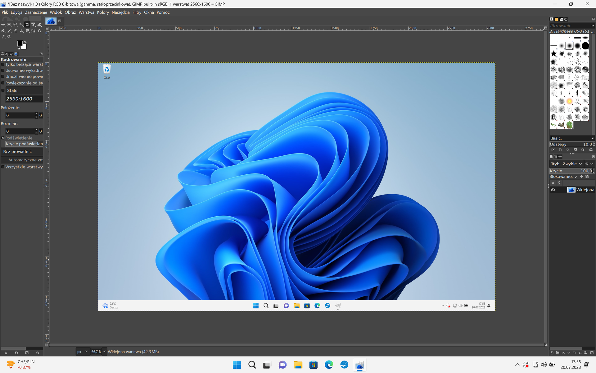 Ilustracja przedstawia okno programu edytora obrazów GIMP. Do programu został wklejony zrzut ekranu pulpitu Windows 11. Na tapecie znajduje się niebieskie logo Windows. Wklejony zrzut obrysowany jest linią przerywaną.