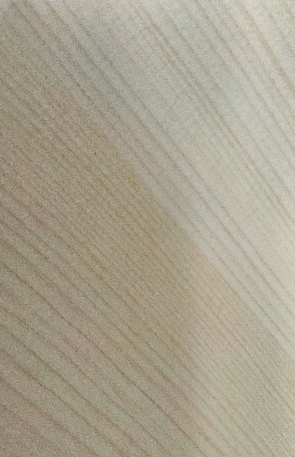 Zdjęcie przedstawia fragment płyty rezonansowej wykonanej z drewna świerkowego. Widoczny jest fragment jasnobrązowej płyty z równoległymi liniami biegnącymi pod lekkim skosem obrazującymi ślady po obróbce drewna.