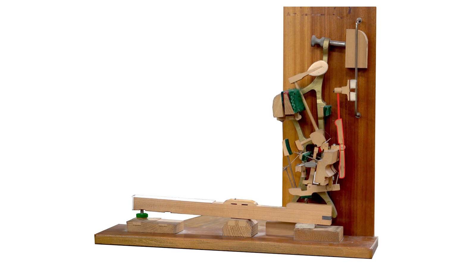 Zdjęcie przedstawia dźwignię tłumikową umieszczoną w mechanizmie pianinowym. Czerwona obwódka wskazuje jej lokalizację.