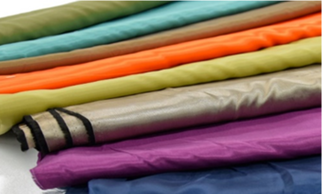 Zdjęcie przedstawia kilka kolorowych, błyszczących, złożonych kawałków materiału ułożonych jeden obok drugiego.Nagranie tożsame z treścią.