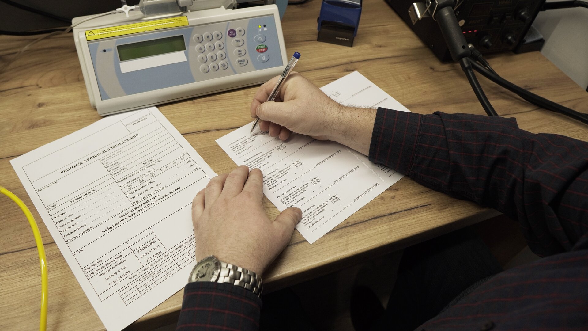 Na zdjęciu technik wypełnienia protokół przeglądu technicznego testowanej pompy infuzyjnej.
