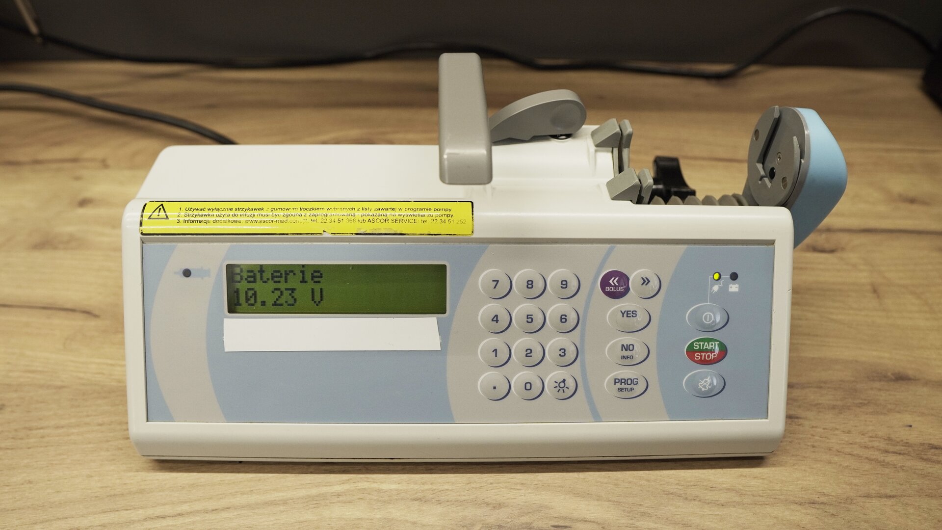 Na zdjęciu technik przeprowadza test akumulatora pompy infuzyjnej. Na ekranie wyświetlana jest informacja: "Baterie 10,23 V".